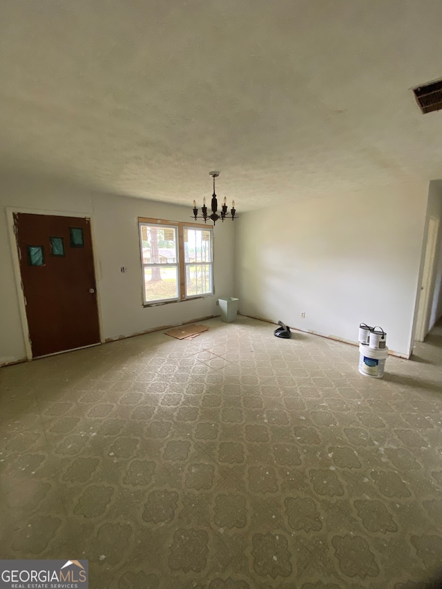 unfurnished living room featuring a chandelier