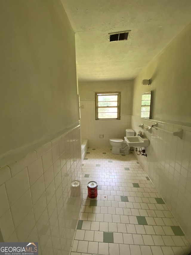 bathroom featuring sink, tile patterned flooring, tile walls, and toilet