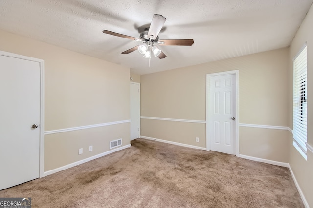 unfurnished room with ceiling fan, light colored carpet, and a textured ceiling