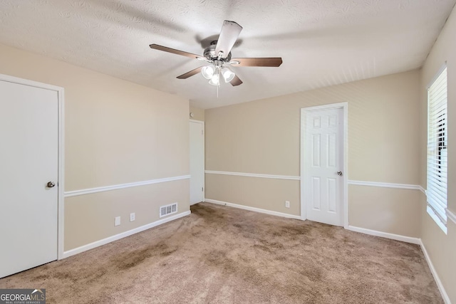 unfurnished bedroom featuring a textured ceiling, baseboards, visible vents, and carpet floors