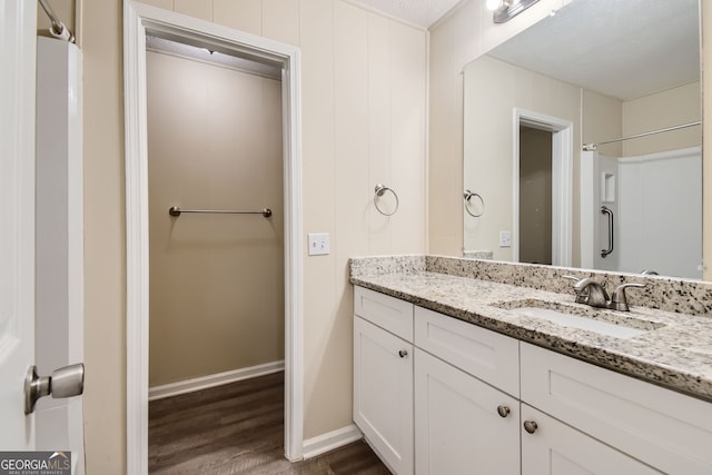 bathroom with a shower, wood-type flooring, vanity, and a textured ceiling