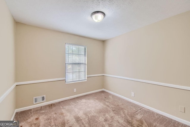 carpeted empty room featuring visible vents, baseboards, and a textured ceiling
