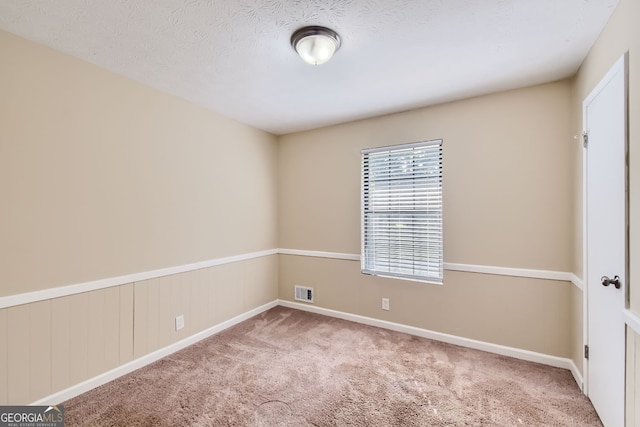 unfurnished room featuring a textured ceiling and light colored carpet