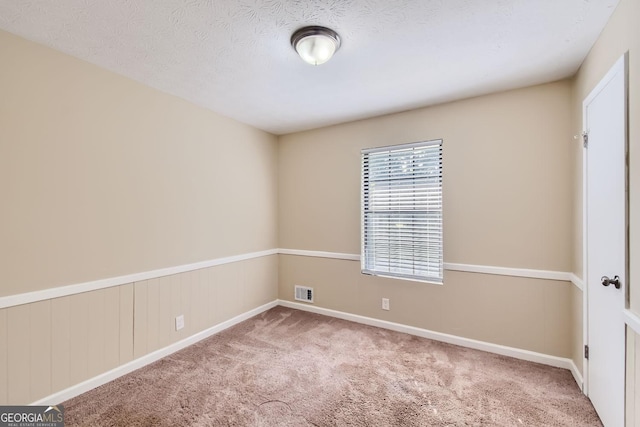unfurnished room featuring carpet flooring, visible vents, and a textured ceiling