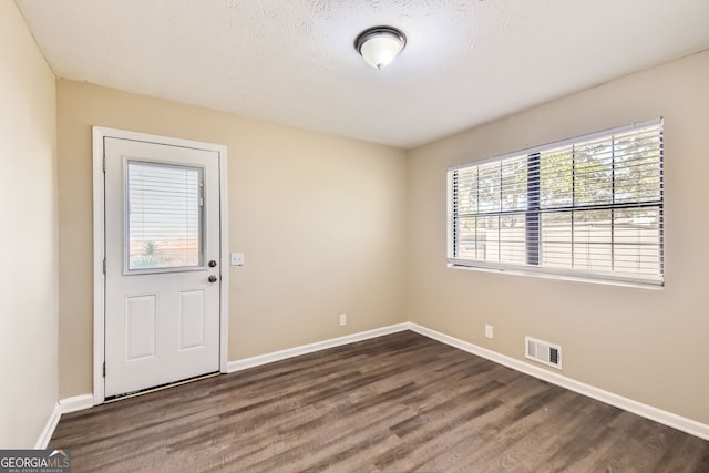 spare room with a textured ceiling and dark hardwood / wood-style flooring