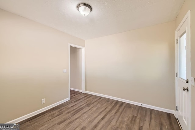 unfurnished room featuring baseboards, a textured ceiling, and wood finished floors