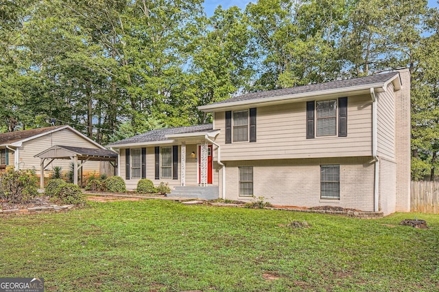 tri-level home featuring brick siding, a front lawn, and fence