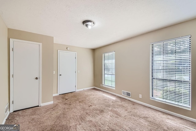 unfurnished bedroom with visible vents, baseboards, carpet floors, and a textured ceiling