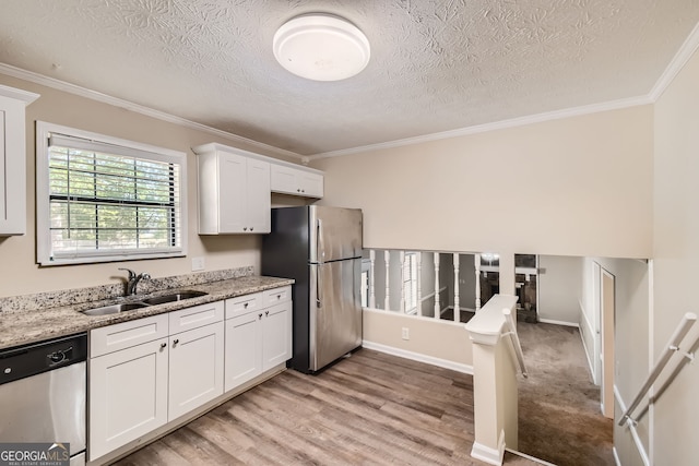 kitchen featuring light wood-type flooring, sink, white cabinetry, stainless steel appliances, and light stone countertops