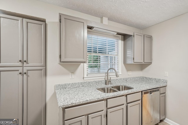 kitchen featuring dishwasher, a textured ceiling, gray cabinets, and a sink