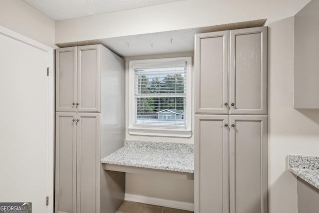 kitchen with light stone countertops, baseboards, and built in study area