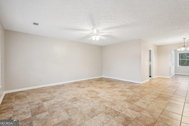 spare room featuring baseboards, visible vents, a textured ceiling, and ceiling fan with notable chandelier