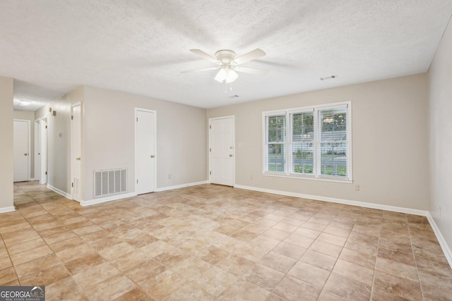 spare room featuring a textured ceiling, a ceiling fan, visible vents, and baseboards