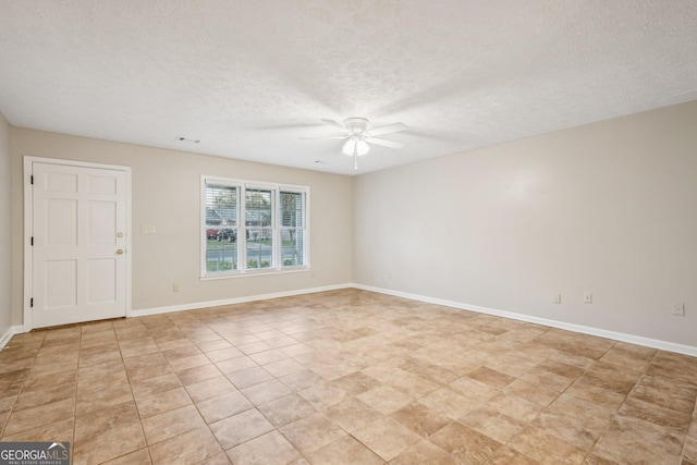 empty room with a textured ceiling, visible vents, a ceiling fan, and baseboards