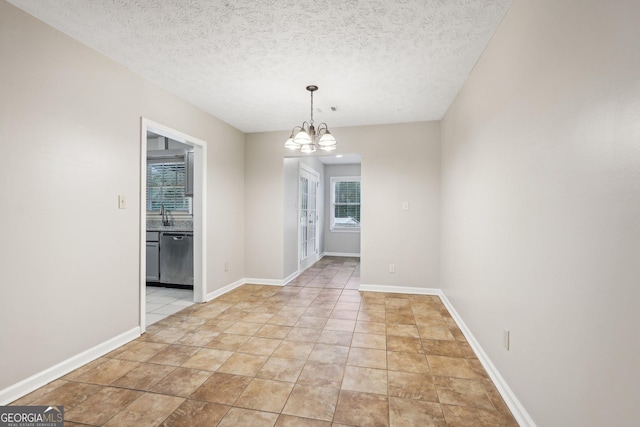 unfurnished dining area featuring baseboards, a textured ceiling, and a notable chandelier