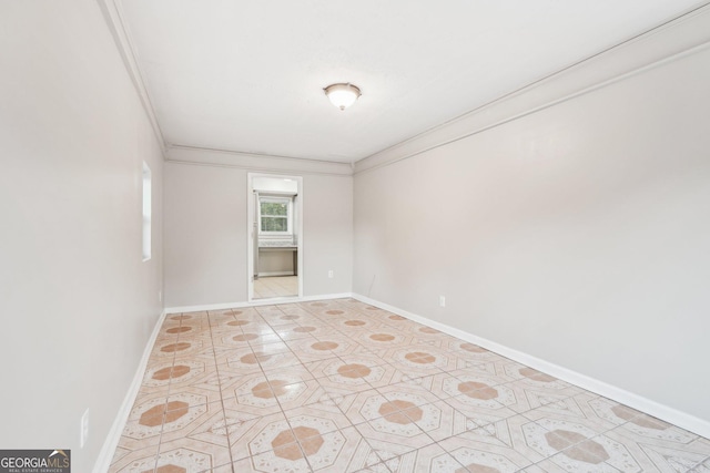 spare room with baseboards and crown molding