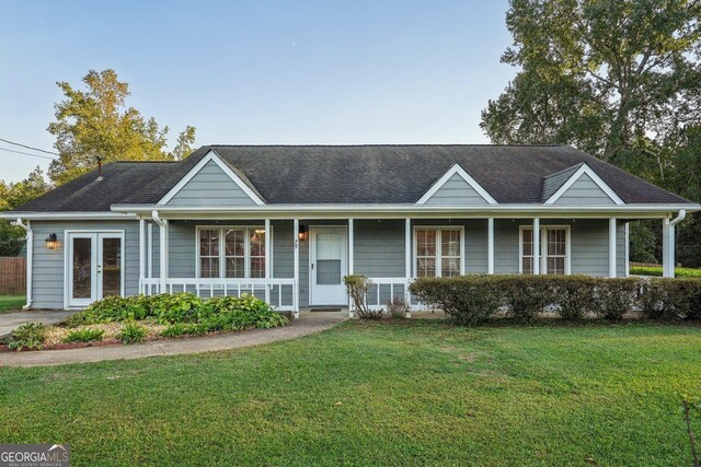 single story home featuring covered porch, french doors, and a front yard