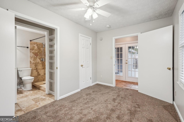 unfurnished bedroom with baseboards, light colored carpet, ensuite bath, a textured ceiling, and french doors