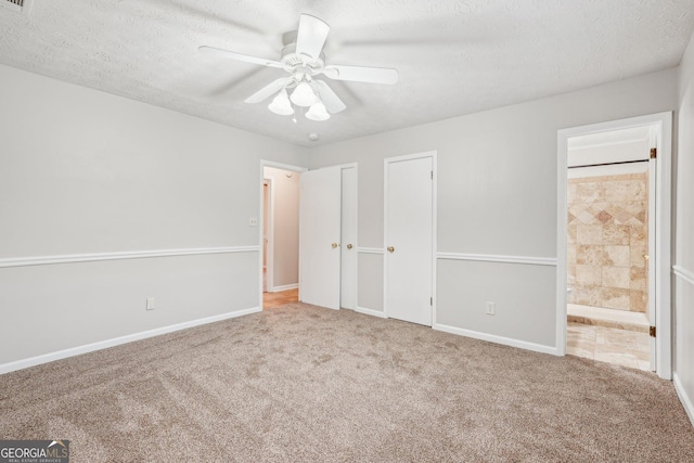 unfurnished bedroom featuring a textured ceiling, carpet flooring, and ensuite bathroom