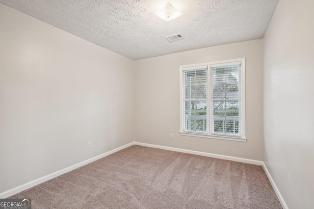 carpeted empty room featuring visible vents, a textured ceiling, and baseboards