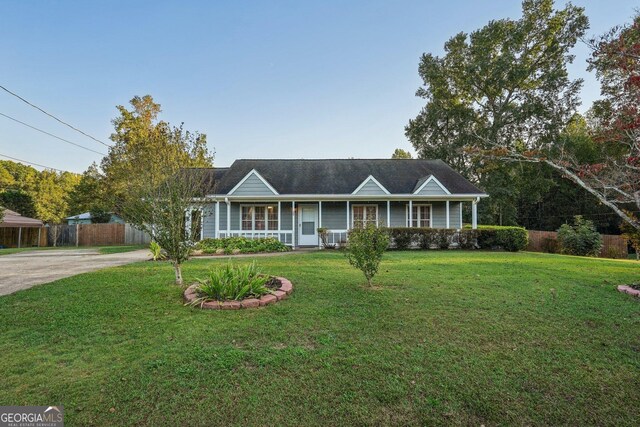 ranch-style house featuring covered porch and a front yard