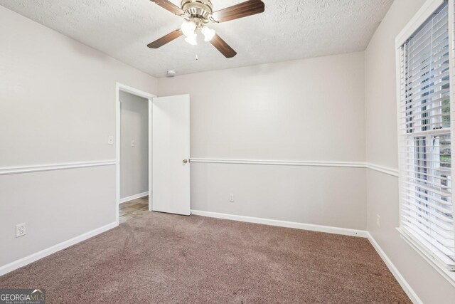 interior space with a textured ceiling, carpet floors, ceiling fan, and baseboards