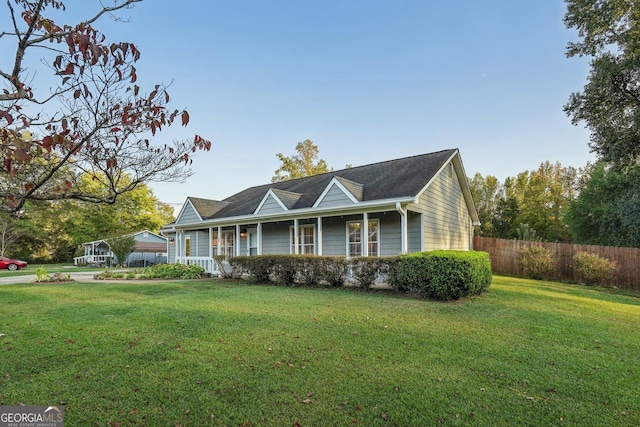 ranch-style house featuring a porch, a front yard, and fence