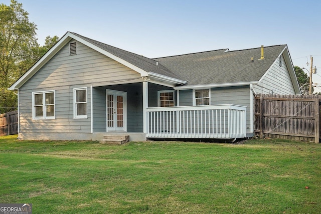 back of house with fence, a lawn, and roof with shingles