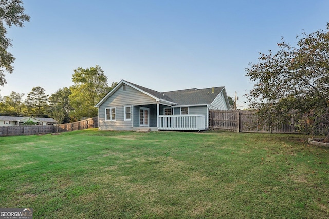 back of property with a fenced backyard, a lawn, and a wooden deck