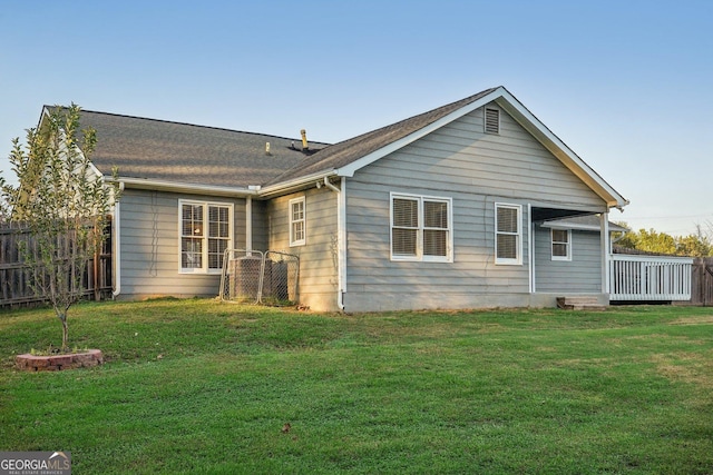 back of property with a yard, a deck, and fence