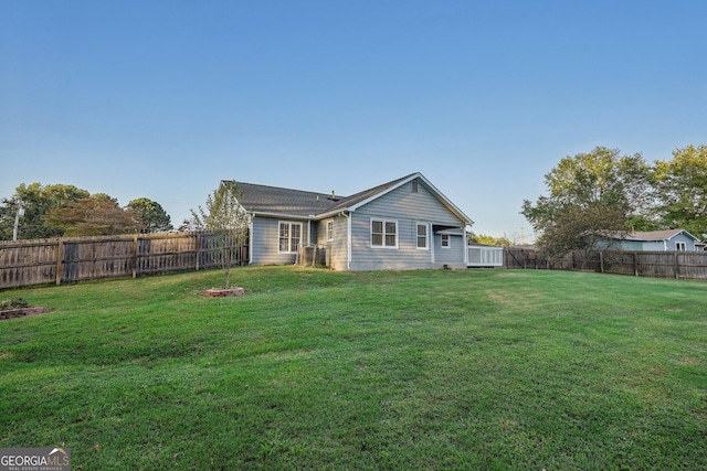 rear view of property featuring a fenced backyard and a lawn