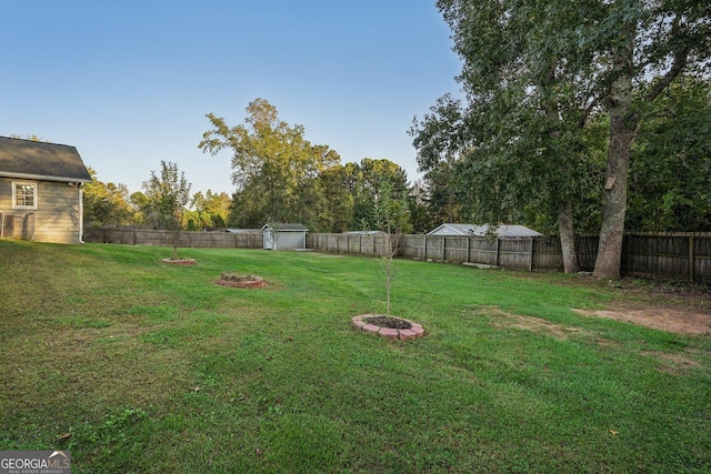 view of yard with a fenced backyard and a fire pit