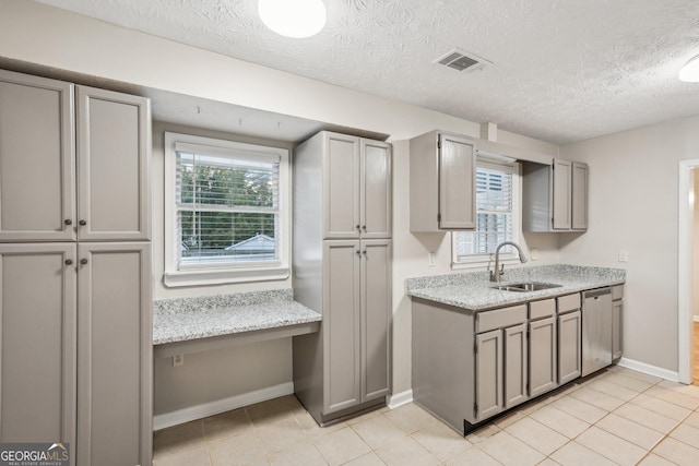 kitchen with dishwasher, gray cabinets, a sink, and built in study area