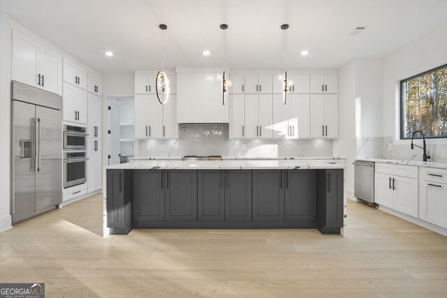 kitchen featuring appliances with stainless steel finishes, sink, white cabinetry, and decorative light fixtures