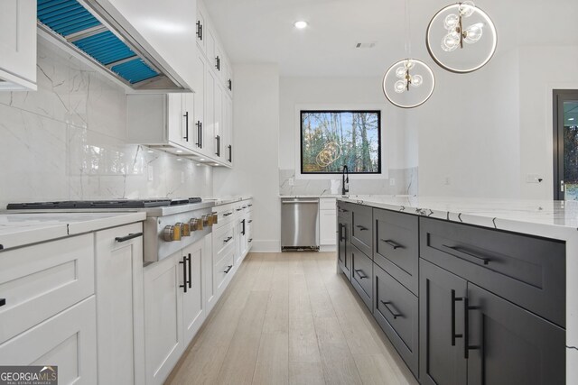 kitchen featuring pendant lighting, white cabinets, stainless steel appliances, light stone counters, and custom range hood