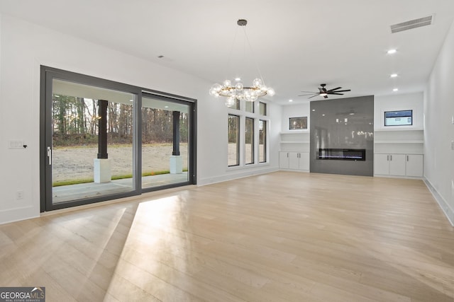 unfurnished living room featuring light wood-type flooring, a fireplace, and ceiling fan with notable chandelier