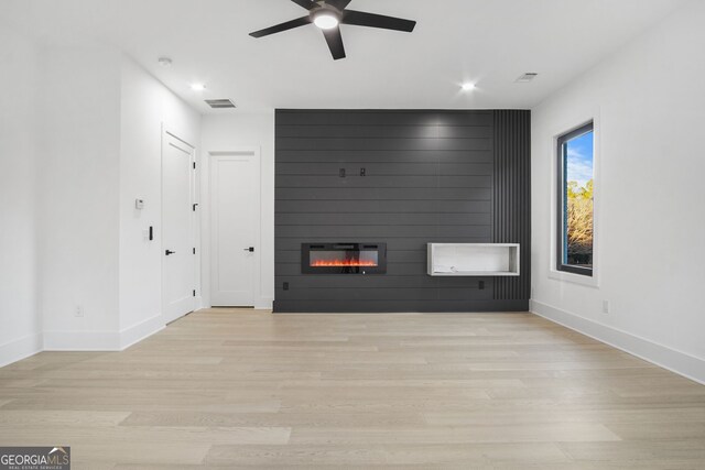 unfurnished living room featuring light hardwood / wood-style floors, a large fireplace, and ceiling fan