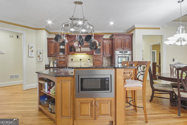 1565 Mountain Shadow Trl, Stone Mountain, GA 30087 - kitchen with a breakfast bar, visible vents, light wood-type flooring, a center island, and appliances with stainless steel finishes