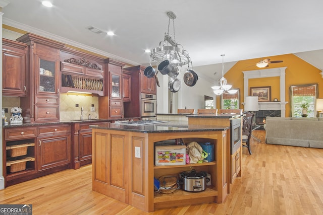 kitchen with a center island, stainless steel appliances, light hardwood / wood-style flooring, decorative light fixtures, and backsplash