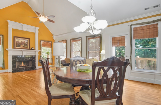 dining room featuring a premium fireplace, ornamental molding, light hardwood / wood-style flooring, and a wealth of natural light