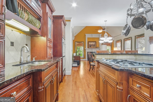 kitchen featuring light hardwood / wood-style floors, tasteful backsplash, decorative light fixtures, stainless steel gas stovetop, and sink