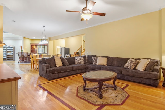 living room featuring crown molding, ceiling fan, and light hardwood / wood-style floors