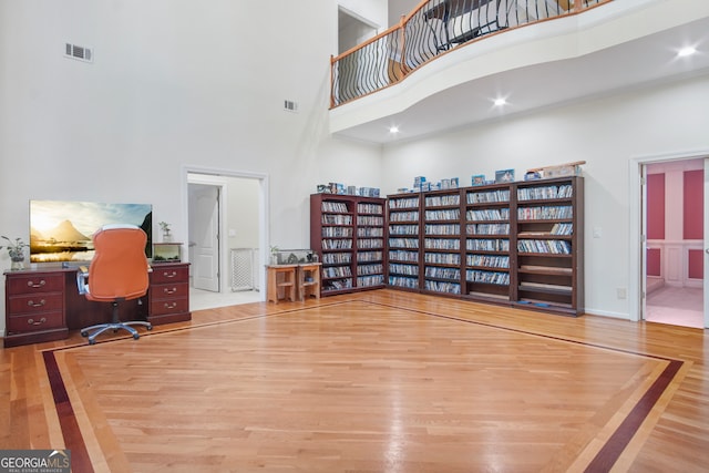 home office with hardwood / wood-style flooring and a towering ceiling