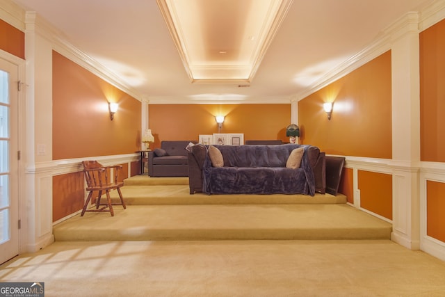 carpeted home theater with a tray ceiling, decorative columns, and ornamental molding