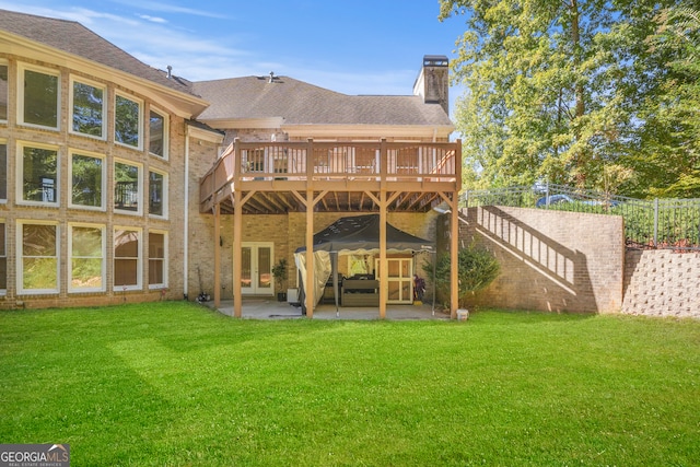 rear view of property with a deck, a lawn, and a patio area