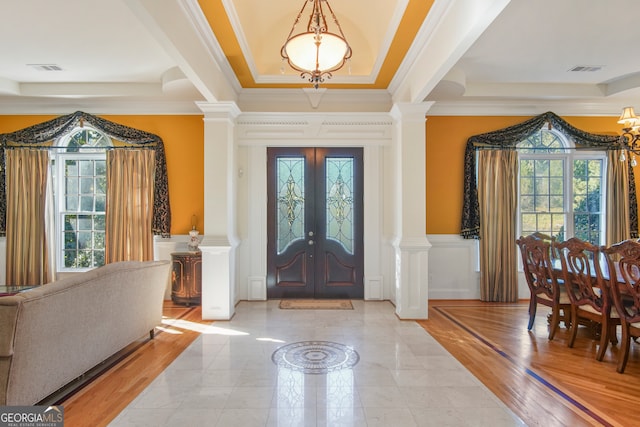 entryway featuring french doors, ornamental molding, a raised ceiling, and light hardwood / wood-style floors