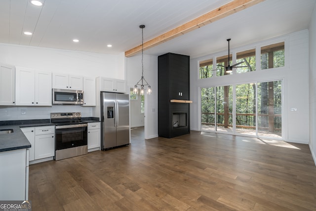 kitchen featuring high vaulted ceiling, stainless steel appliances, white cabinets, dark hardwood / wood-style flooring, and hanging light fixtures