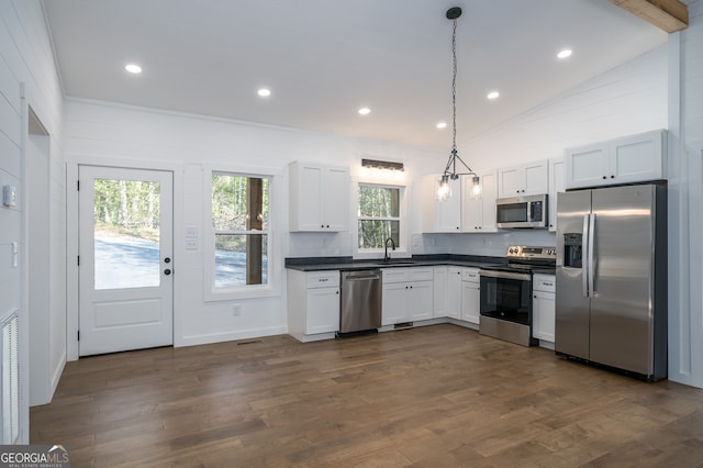 kitchen with appliances with stainless steel finishes, a healthy amount of sunlight, vaulted ceiling with beams, and hanging light fixtures