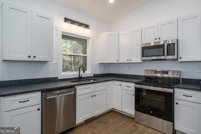 kitchen featuring sink, vaulted ceiling, stainless steel appliances, and white cabinets