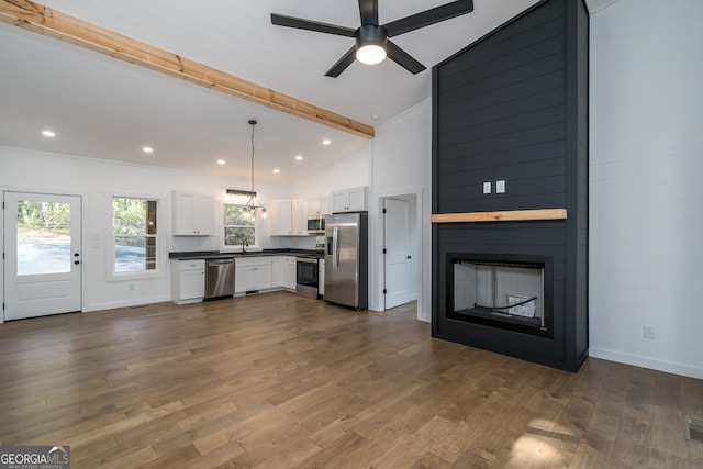 kitchen with white cabinets, hanging light fixtures, stainless steel appliances, lofted ceiling with beams, and dark hardwood / wood-style flooring